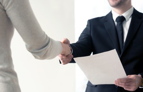 Händedruck beim Vorstellungsgespräch mit Unterlagen 