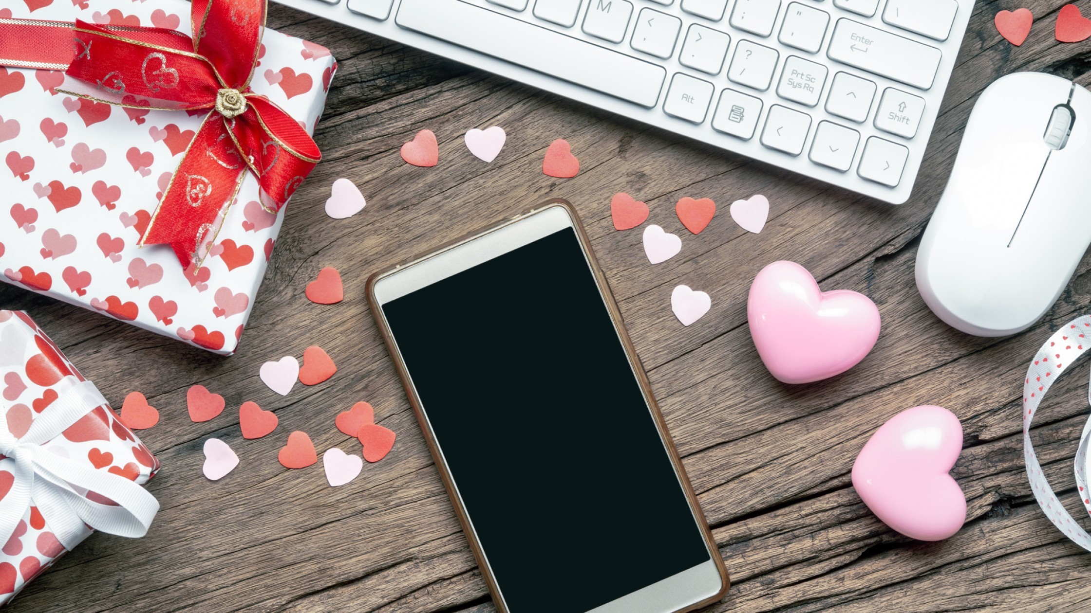 Mobile phone and laptop surrounded by gifts and colorful hearts 
