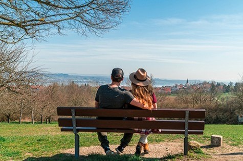 A couple sitting on a bench, peacefully enjoying the scenic view over Lake Constance on a clear day