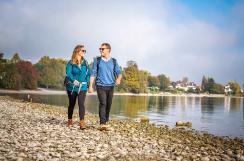  Two couples hiking together along Lake Constance near Konstanz on a sunny day.