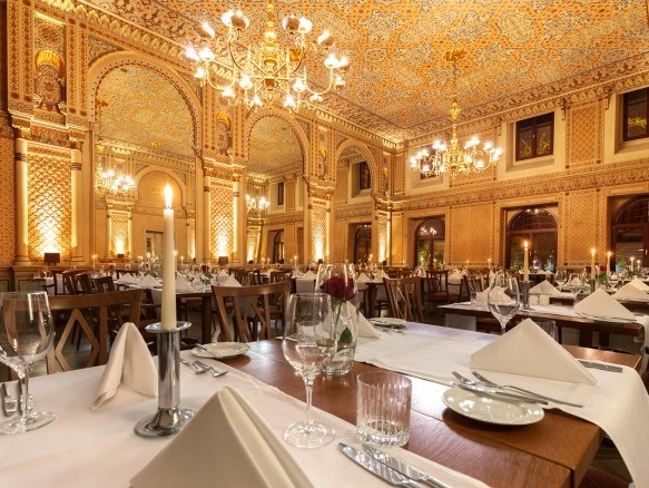  Tables set with red roses and candles in the festive Moorish hall, with a view of the gigantic mirrors and the wonderful wall decorations.