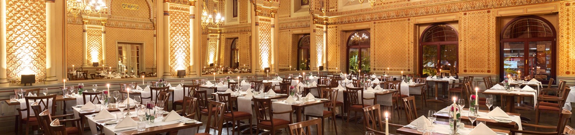  Tables set with red roses and candles in the festive Moorish hall, with a view of the gigantic mirrors and the wonderful wall decorations.
