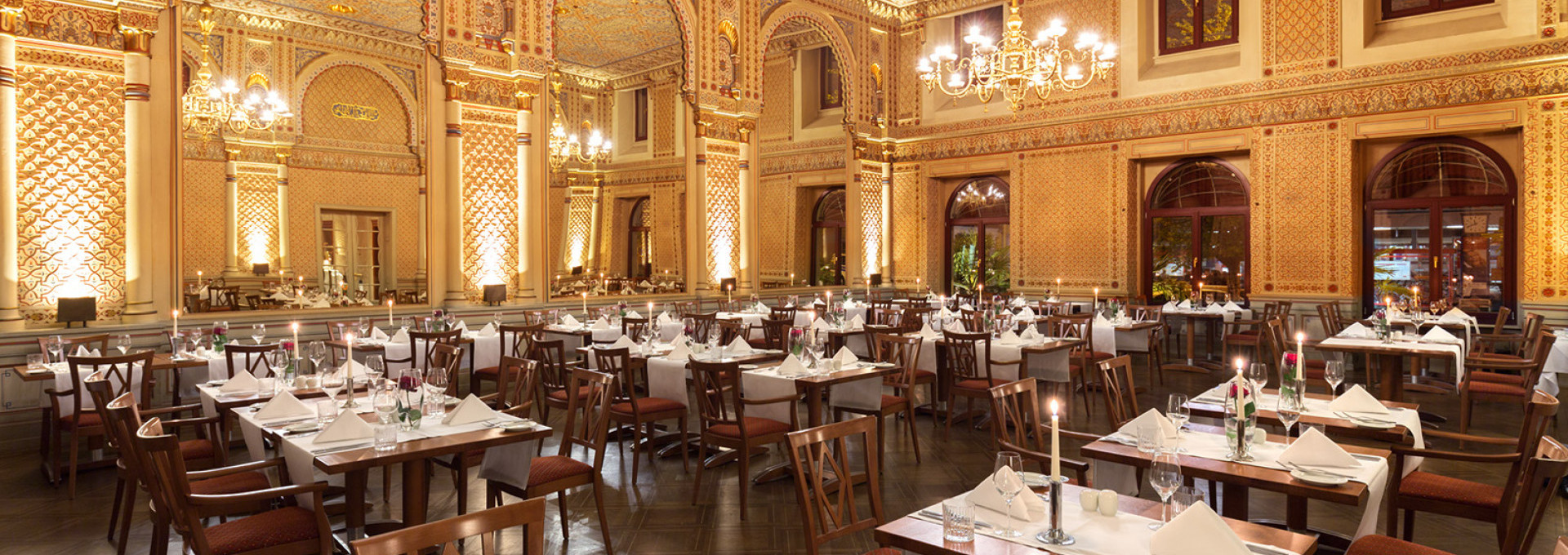  Gedeckte Tische mit roten Rosen und Kerzen im festlichen maurischen Saal, mit Blick auf die gigantischen Spiegeln und die wundervolle Wanddekoration. 