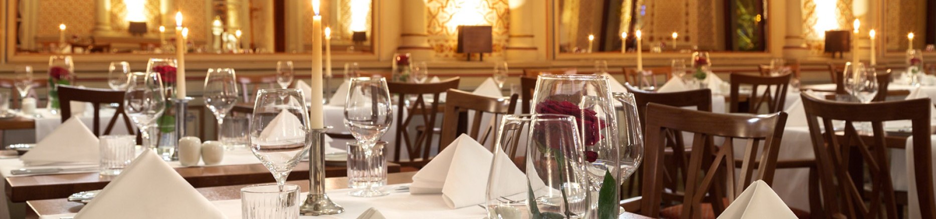  Gedeckte Tische mit roten Rosen und Kerzen im festlichen maurischen Saal, mit Blick auf die gigantischen Spiegeln und die wundervolle Wanddekoration. 