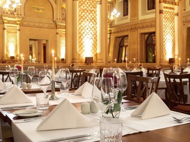 Gedeckte Tische mit roten Rosen und Kerzen im festlichen maurischen Saal, mit Blick auf die gigantischen Spiegeln und die wundervolle Wanddekoration.