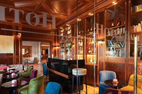 Hotel bar with small tables and cozy loungers, overlooking the entrance area.