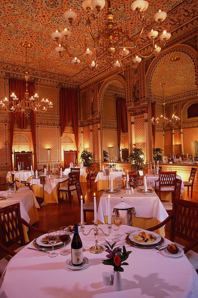 Festive hall with ornate ceiling with elaborate pattern and large chandeliers as well as mirrors almost five meters high.
