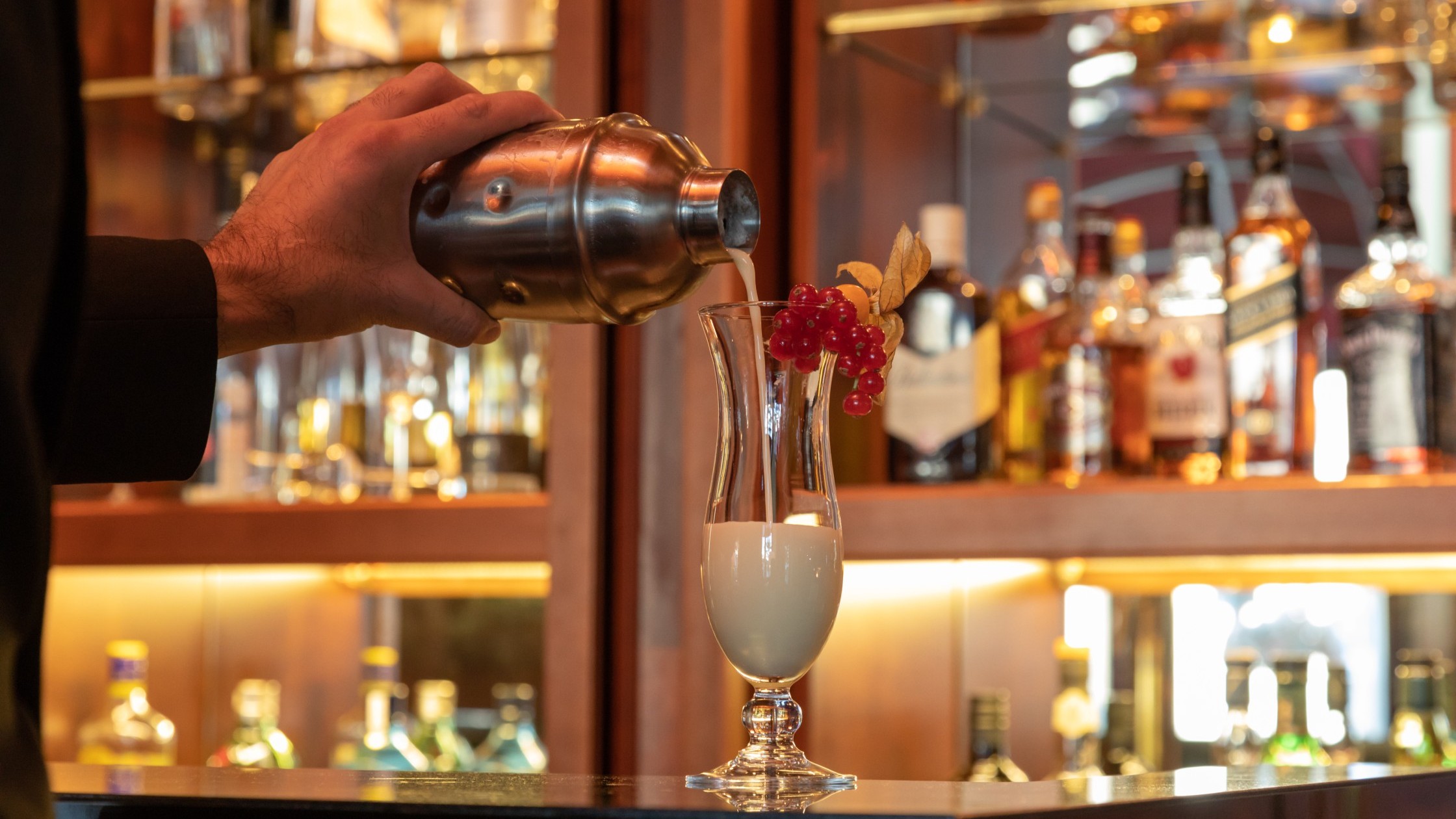  Freshly prepared Pina Colada is poured from the shaker into a cocktail glass in the bar.