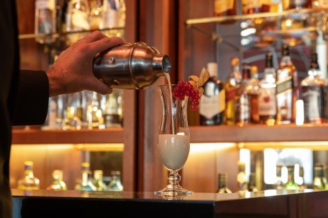 Freshly prepared Pina Colada is poured from the shaker into a cocktail glass in the bar.