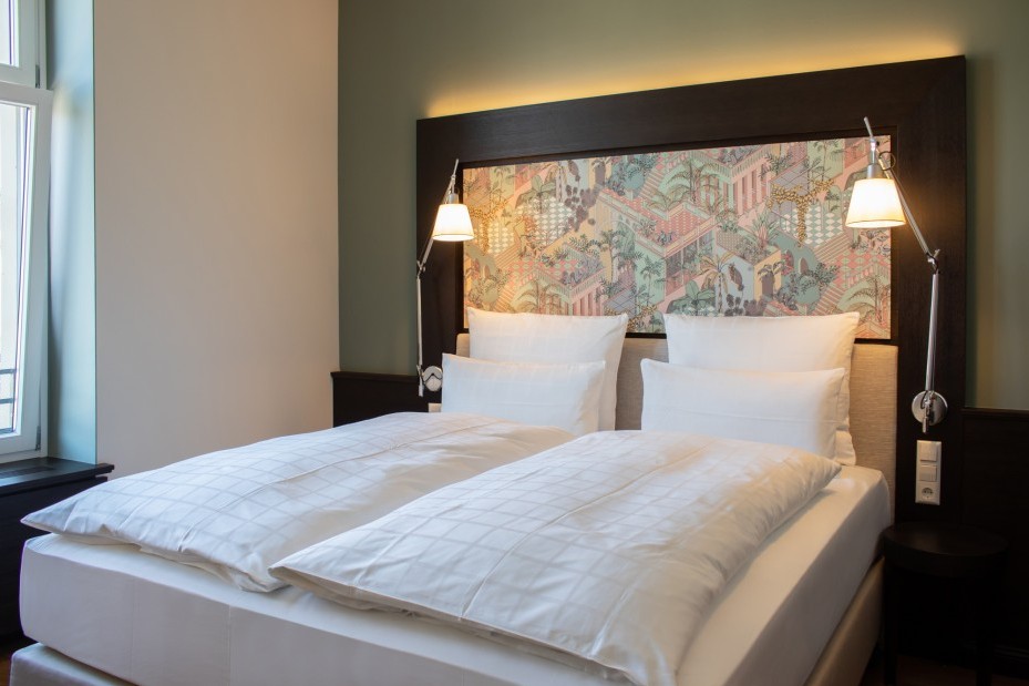 Elegantes Doppelbett mit hochwertiger Bettwäsche im stilvoll eingerichteten Zimmer des Hotels Alte Post