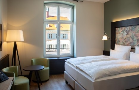 Modernly furnished hotel room with double bed, marble bathroom, and cozy seating area at Hotel Alte Post in Konstanz