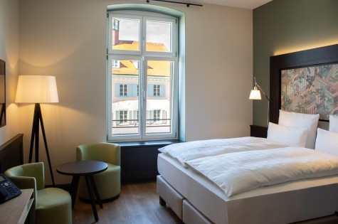 Modernly furnished hotel room with double bed, marble bathroom, and cozy seating area at Hotel Alte Post in Konstanz